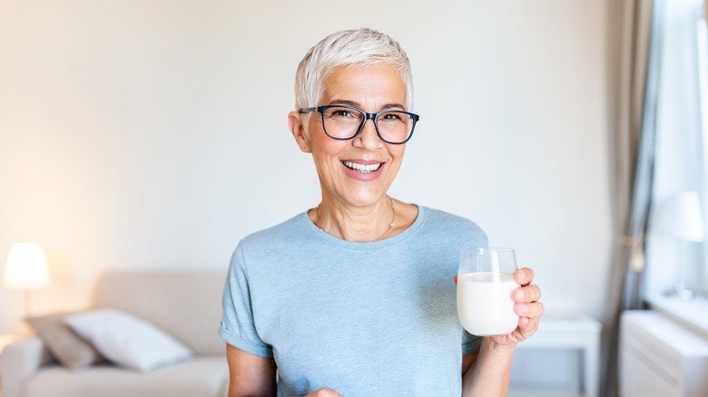 A smiling woman holding a glass of milk 