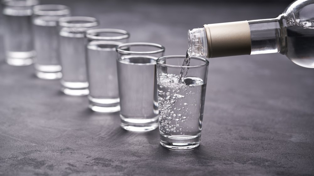 A bottle of vodka pouring shots into glasses