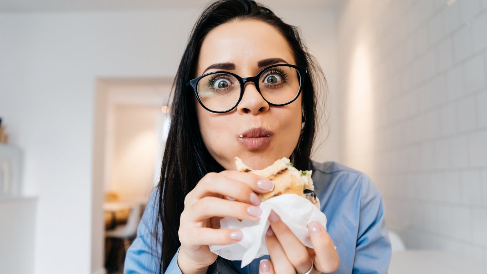 Woman eating deli meat sandwich 