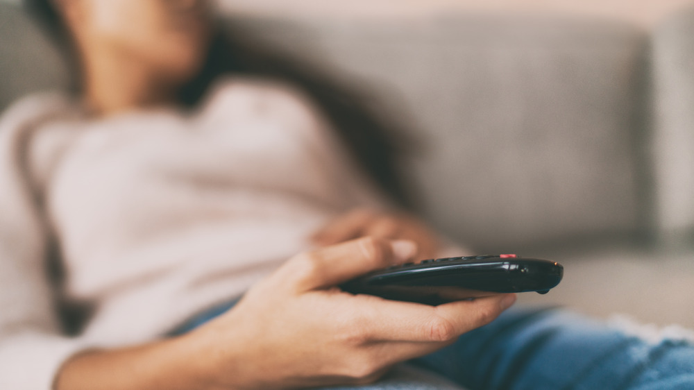 Woman asleep on a couch holding a remote