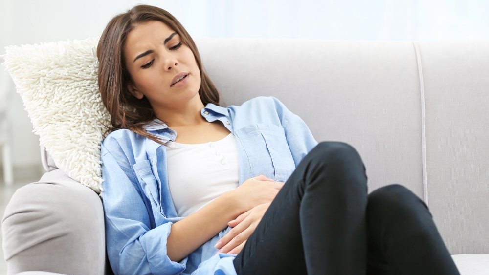 Young woman touching abdomen in pain 