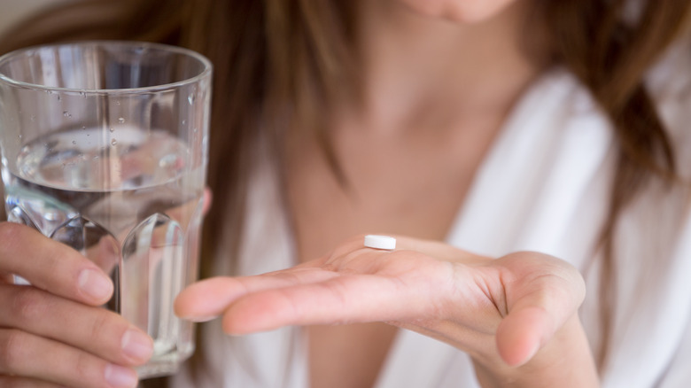 Woman holding pill and water