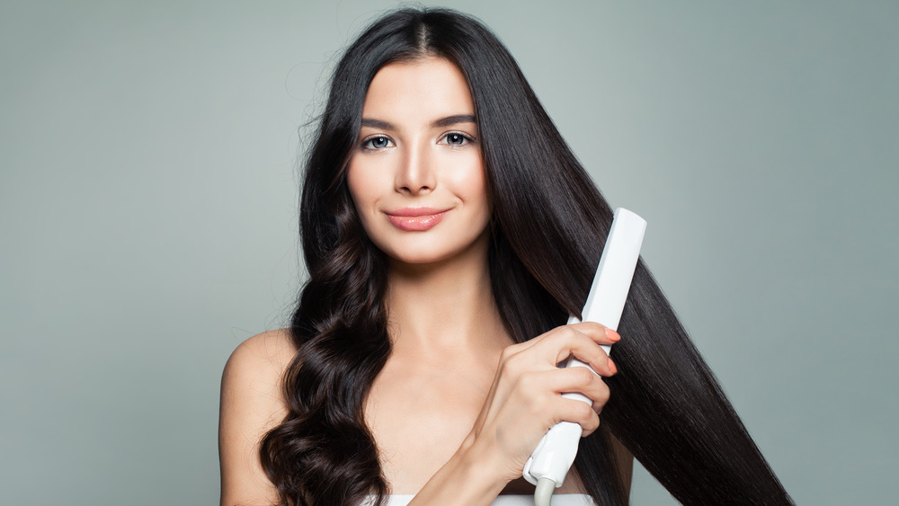 Brunette woman straightening hair