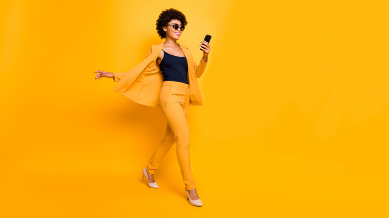 A woman walking in high heels with a yellow bakcground