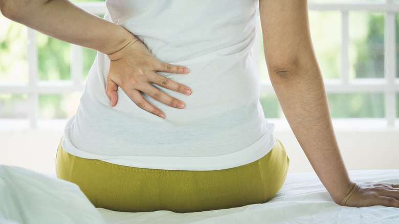 A woman touching her back, suffering from back pain