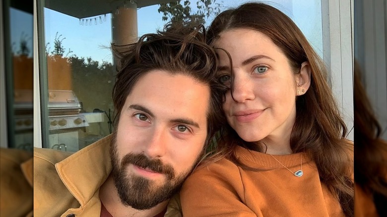 Chris McNally and Julie Gonzalo pose in front of a window.