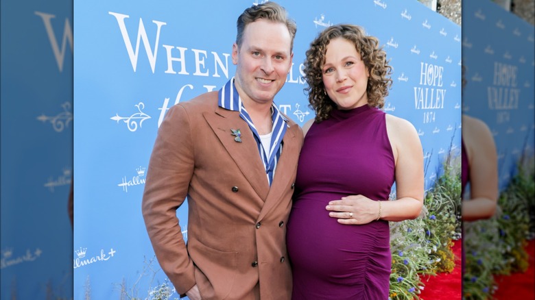 Pregnant Erin Krakow poses next to Ben Rosenbaum with her hand on her baby bump.