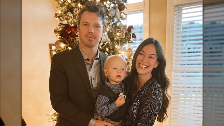 Daniel Stine and Rachel Hendrix hold their son in front of a Christmas tree.