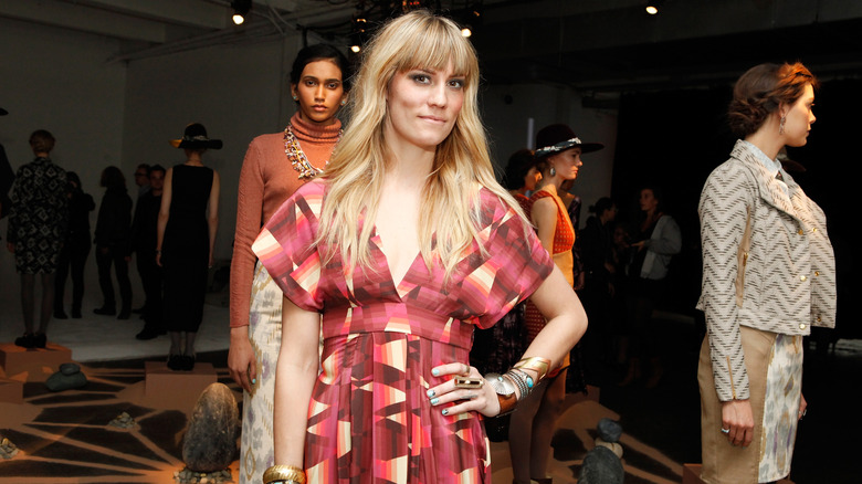 Gretchen Jones posing at Mercedes-Benz Fashion Week in 2012 with models in the background.