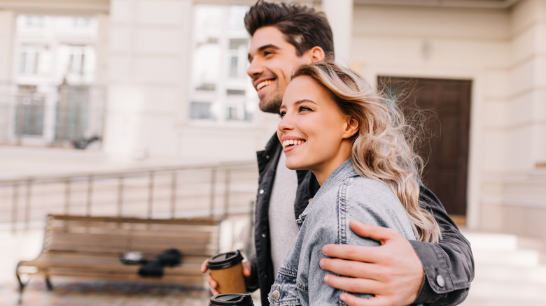 happy couple walking with coffees