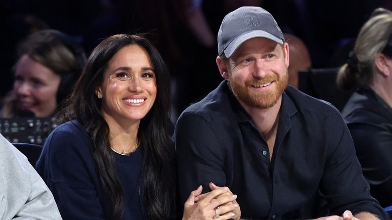 Harry and Meghan with arms locked watching a basketball game