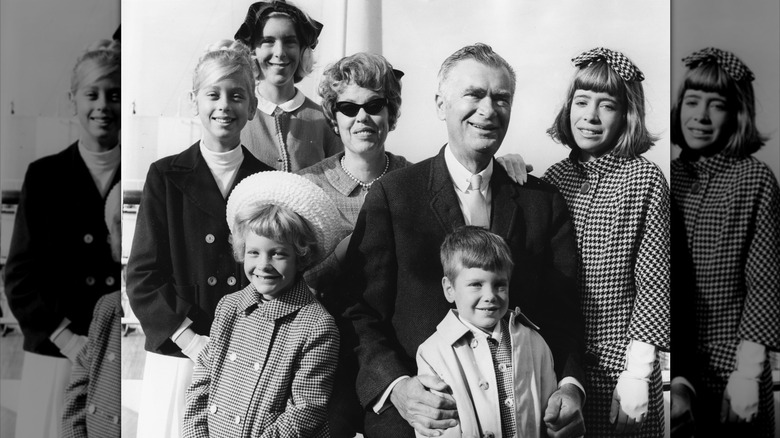 Buddy Ebsen smiles standing in the middle of five of his children and his wife in a black-and-white photo