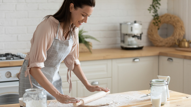 Woman baking in her kitchen using a rolling pin