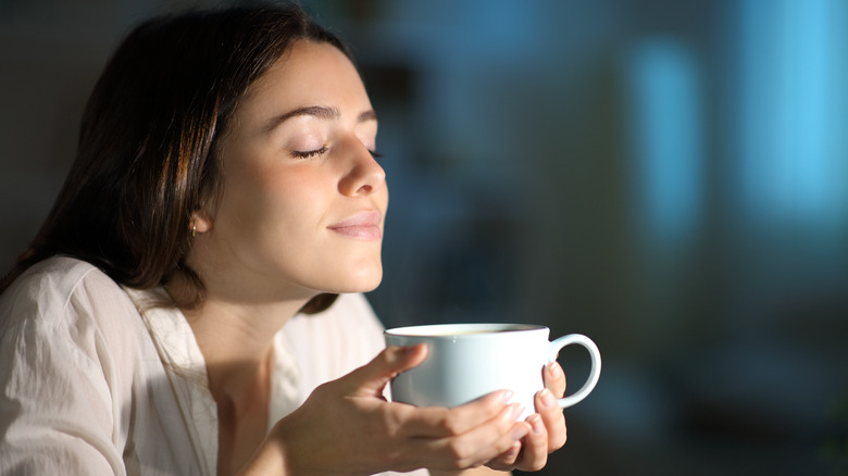 Woman smelling cup of coffee