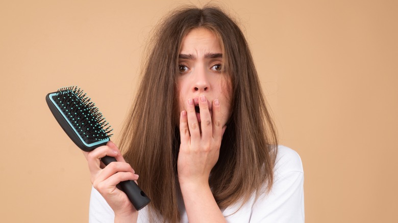 Woman with frizzy hair holding a hairbrush
