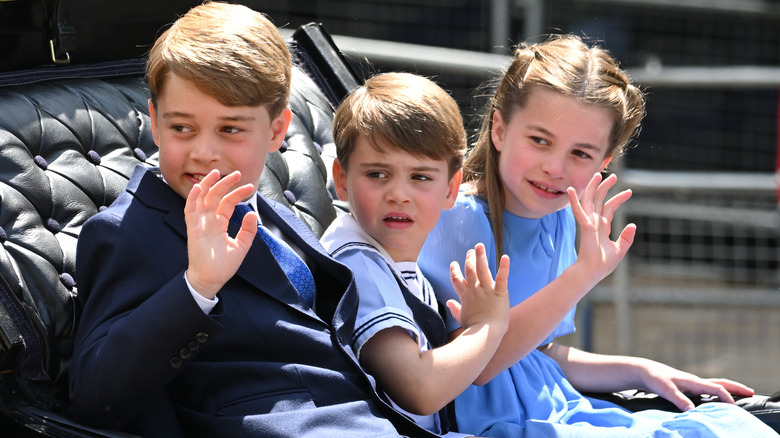 Prince George, Prince Louis, and Princess Charlotte waving at crowds from a carriage