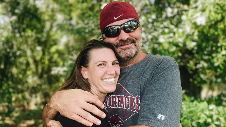 Amanda Brumfield outdoors being hugged by her husband