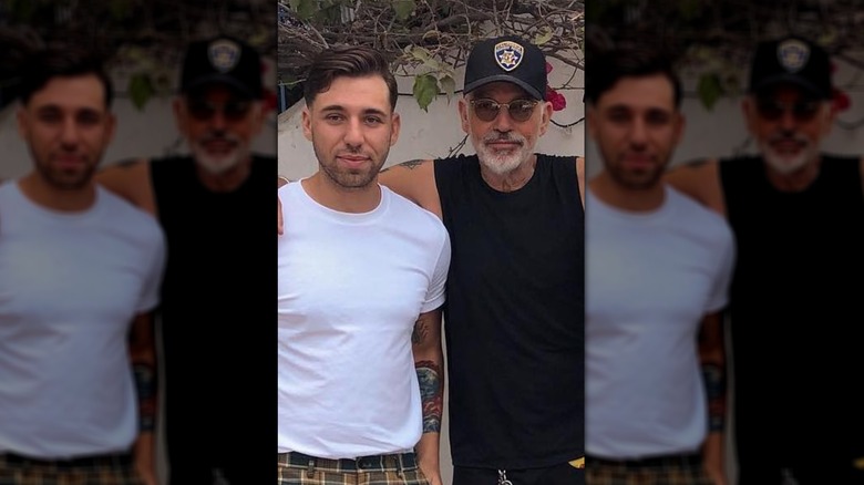 Harry James Thornton in purple hoodie and black ball cap unsmiling sitting in chair