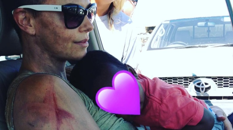 Charlize Theron holding her baby daughter in a car on the set of Mad Max: Fury Road
