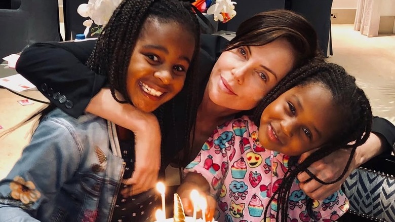 Charlize Theron embracing her daughters in front of a birthday cake