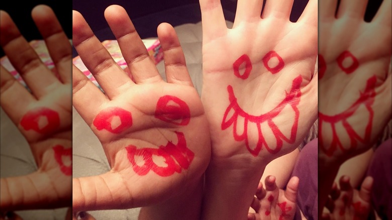 Charlize, Jackson, and August Theron's hands with painted smiley faces
