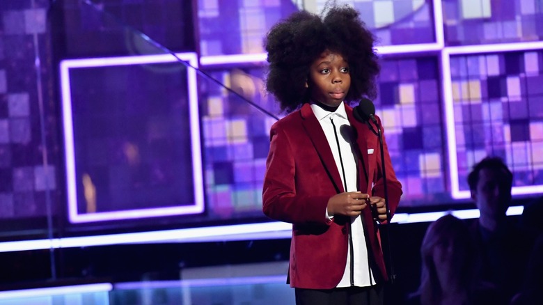 Raif-Henok Emmanuel Kendrick in a red blazer introducing his grandmother at the Grammys