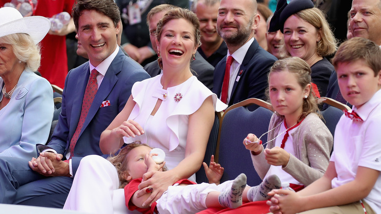 Justin Trudeau and Sophie Gregoire sit at an event with their three kids as children
