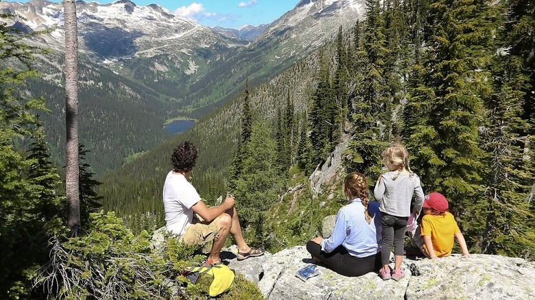 Justin Trudeau and and Sophie Gregoire sit next to two of their kids with their backs to the camera overlooking a mountain
