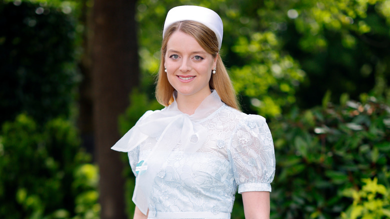 Flora Vesterberg smiles wearing a white dress and white hat outside