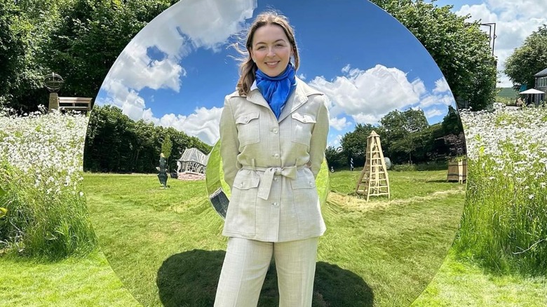 Zenouska Mowatt posing in a garden and standing in front of a large circular mirror