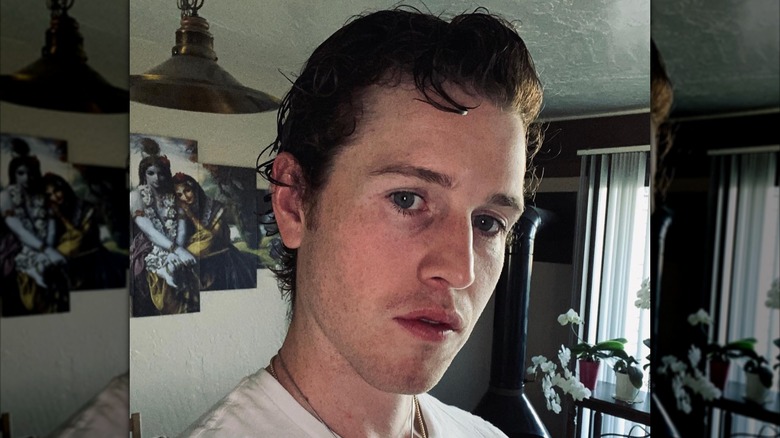 Sean O'Neal posing for a photo in his home with Hindu deity poster in background