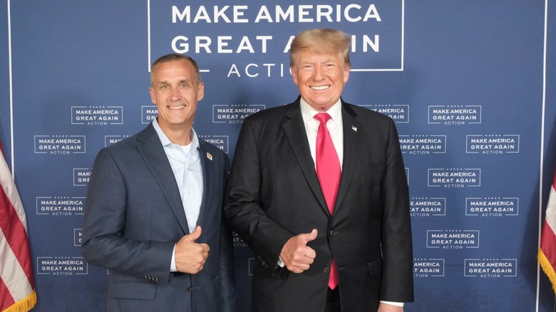 Corey Lewandowski and Donald Trump smiling against "Make America Great Again" seamless and giving thumbs up