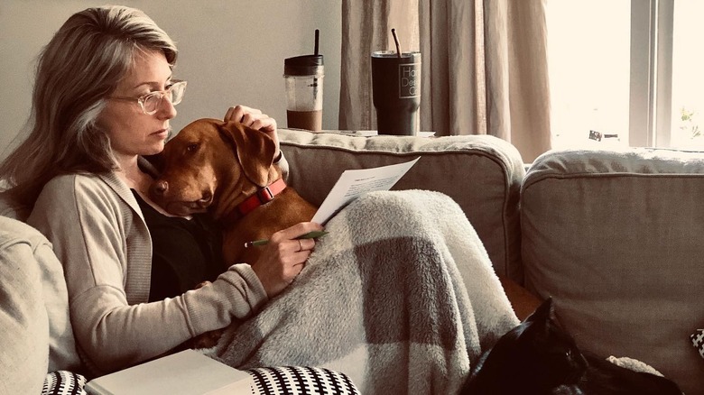Kelly Harp reads sitting on the couch with her pets