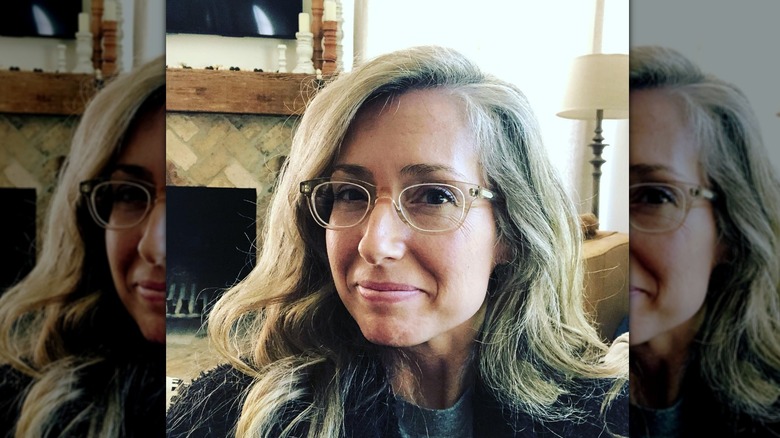 Kelly Harp smiles wearing her hair down in glasses at her house