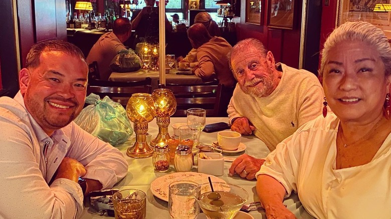 Jon Gosselin with his mother and older gentleman smiling over dinner table in restaurant