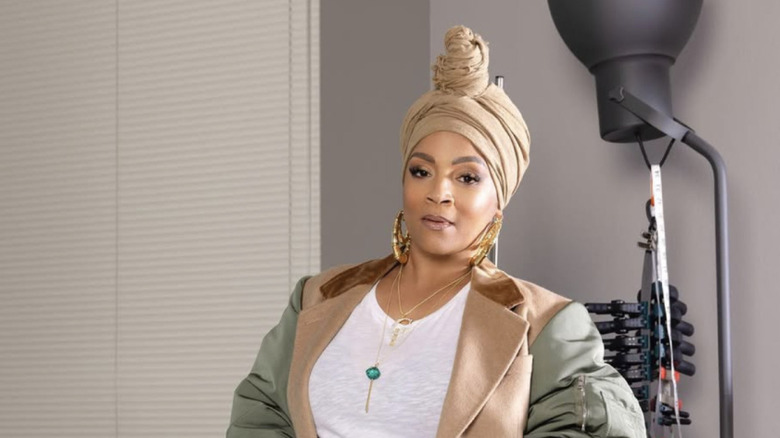 Simone I. Smith posing in a tan turban and her lollipop pendant