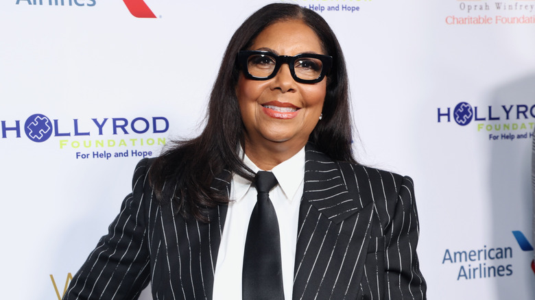 Cookie Johnson smiling in striped jacket and glasses at event