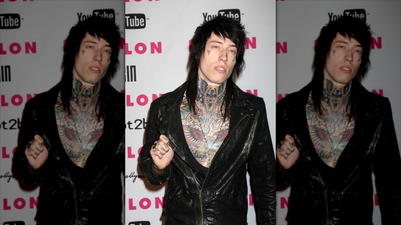 Trace Cyrus posing in a leather jacket on a YouTube step-and-repeat