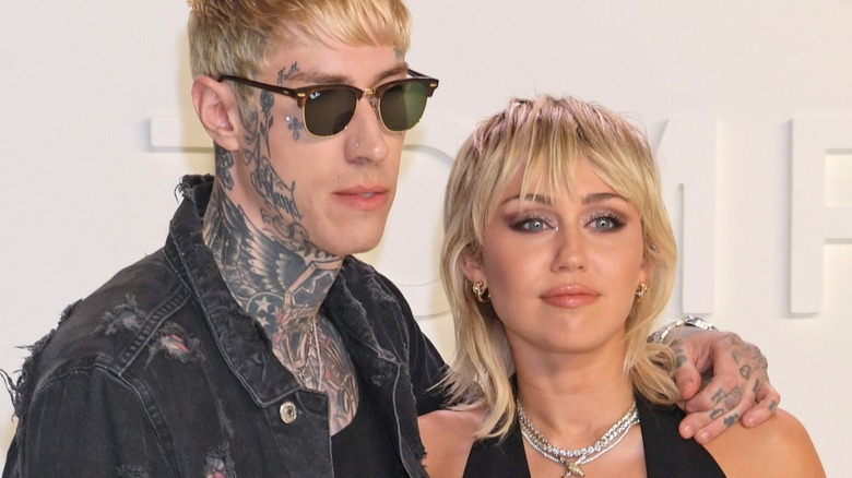Trace with his arm around Miley Cyrus on a Tom Ford step and repeat