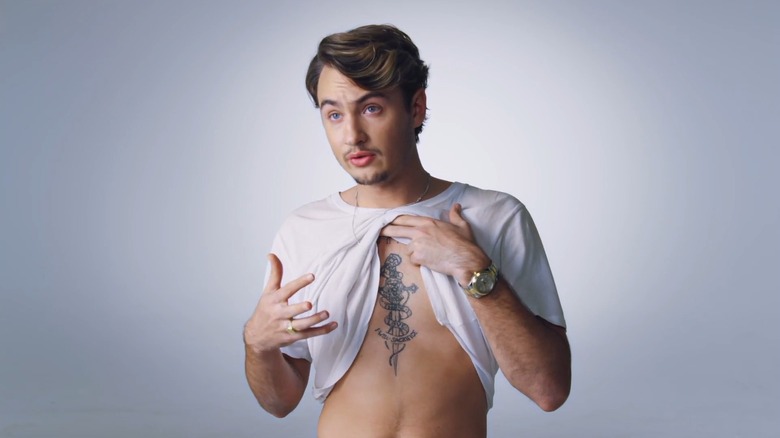 Brandon Thomas Lee lifting up his shirt to show off his chest tattoo