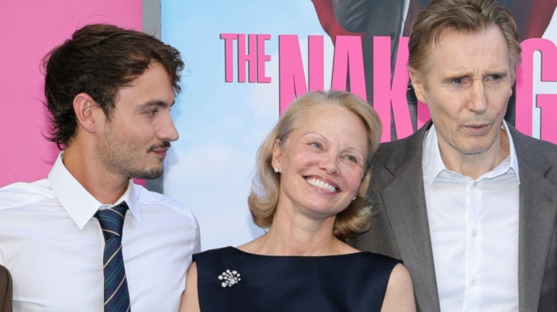 Brandon Thomas Lee looking at his mother, who is laying her head on Liam Neeson's shoulder, at The Naked Gun premiere