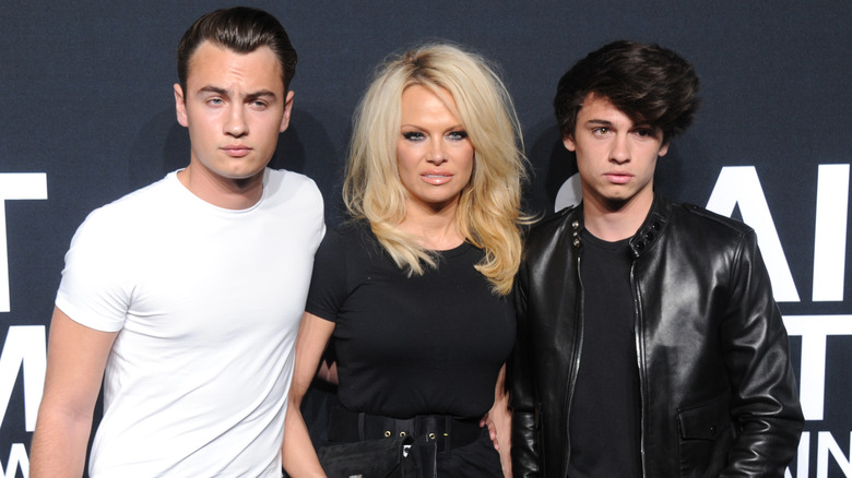 Brandon Thomas Lee, Dylan Jagger Lee, and Pamela Anderson smiling at a Saint Laurent show in 2016