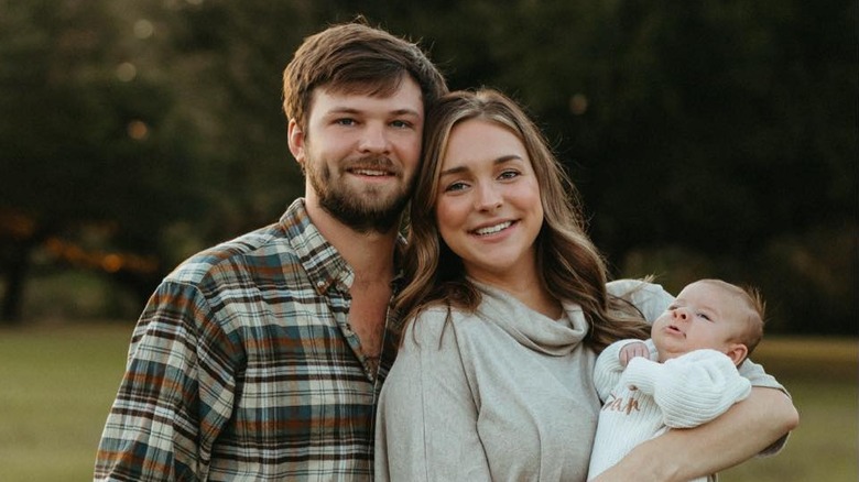 Morgan Doughty Bostick stands next to her husband Batten Bostick holding their baby girl outside.