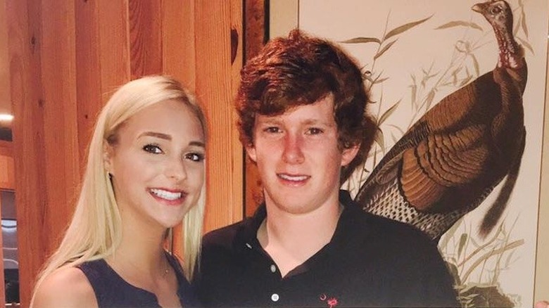 Morgan Doughty Bostick stands next to Paul Murdaugh behind a picture of a turkey smiling when they were in high school.