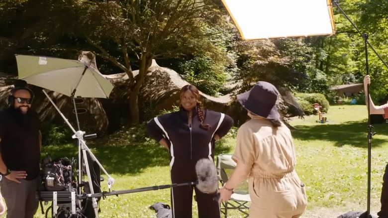 Retta standing on a lawn with film crew on set of "Ugliest House in America"