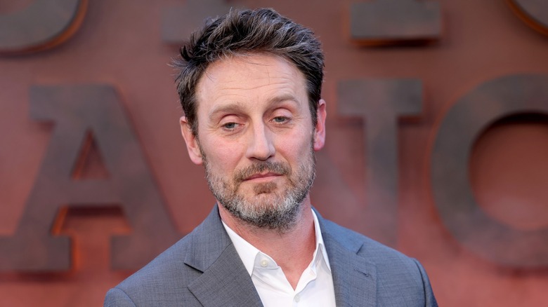 Josh Stewart wearing a grey suit while posing at the 'Dutton Ranch' premiere