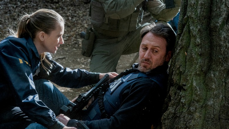 A.J. Cook and Josh Stewart wearing FBI outfits in a woodland area