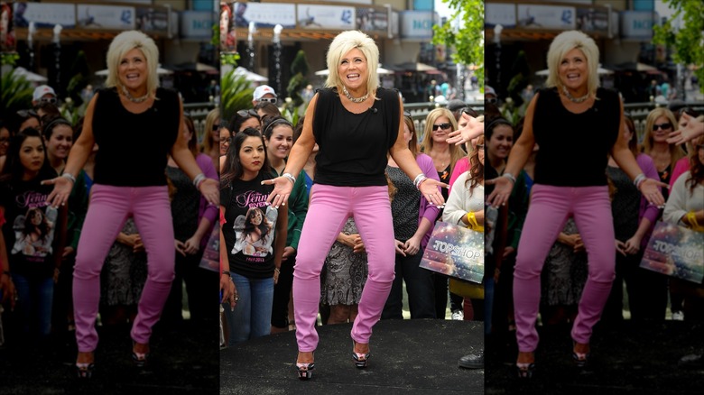Theresa Caputo shrugging in pink pants in front of a crowd