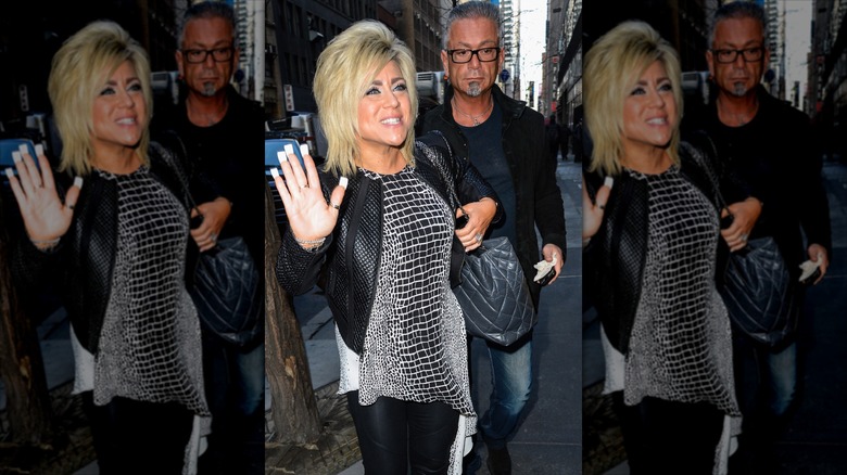 Theresa Caputo holding up her hand to a street photographer, joined by Larry Caputo