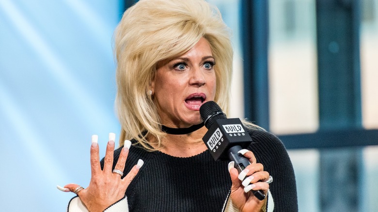 Theresa Caputo looking scandalized while holding a microphone that says BUILD